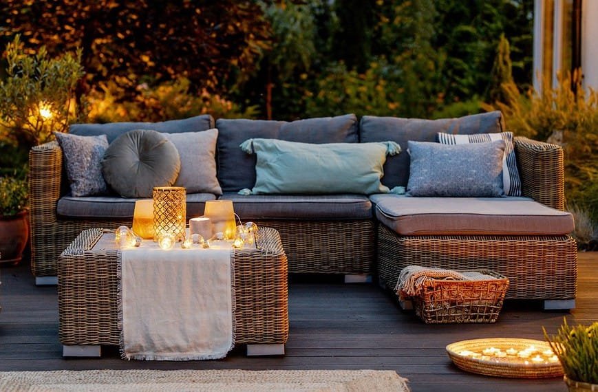 Meubles en osier sur une terrasse en bois avec des bougies, mettant en valeur les meilleurs tapis design d'extérieur.